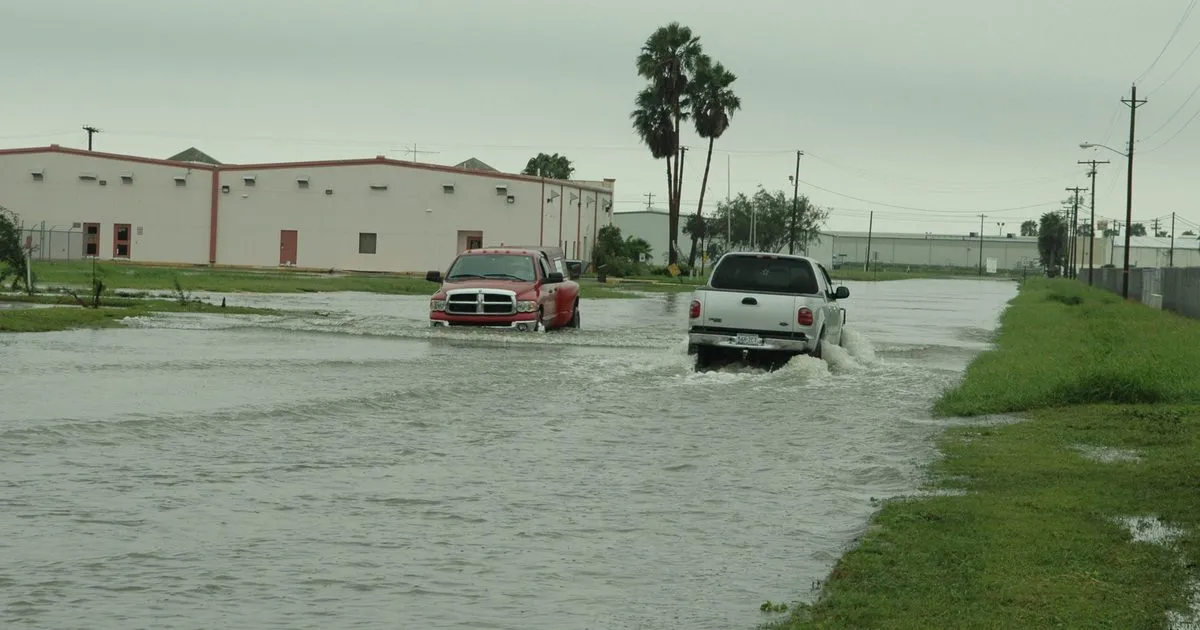 Pickup trucks driving through a flooded street the day after a hurricane in Texas
