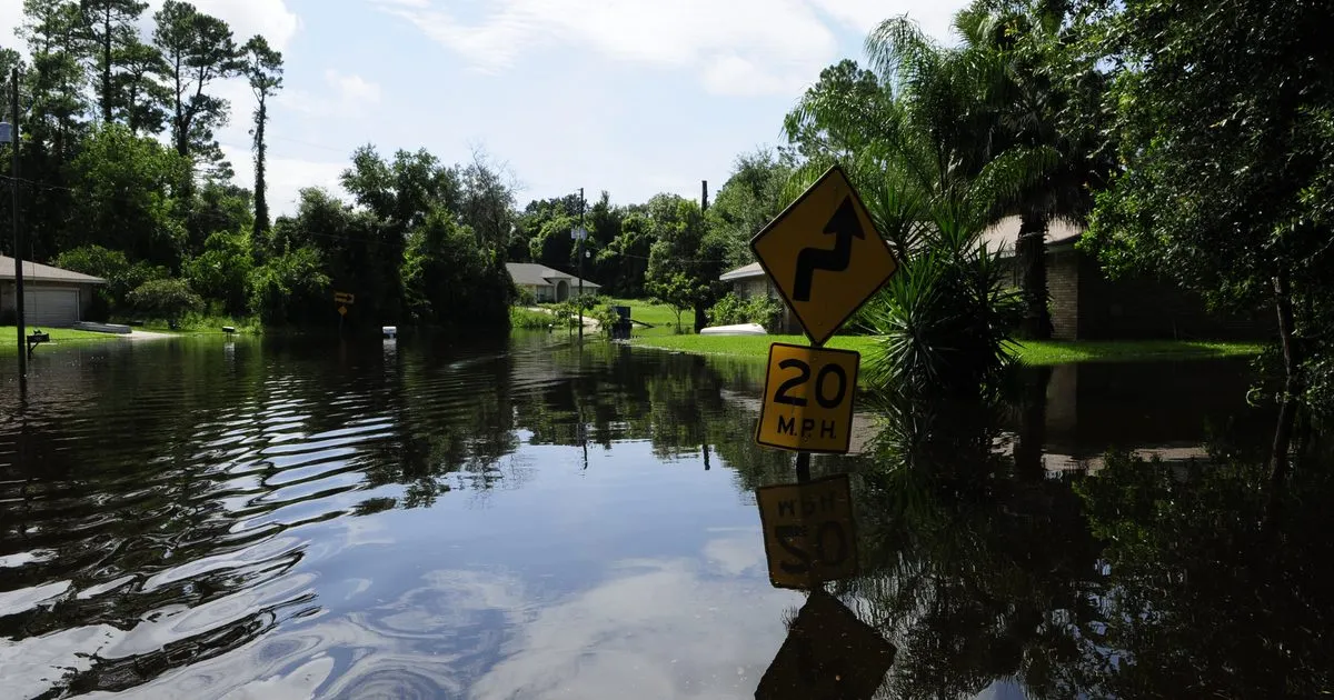 A flooded residential street with a submerged speed limit sign after Tropical Storm Fay in Deltona, Florida