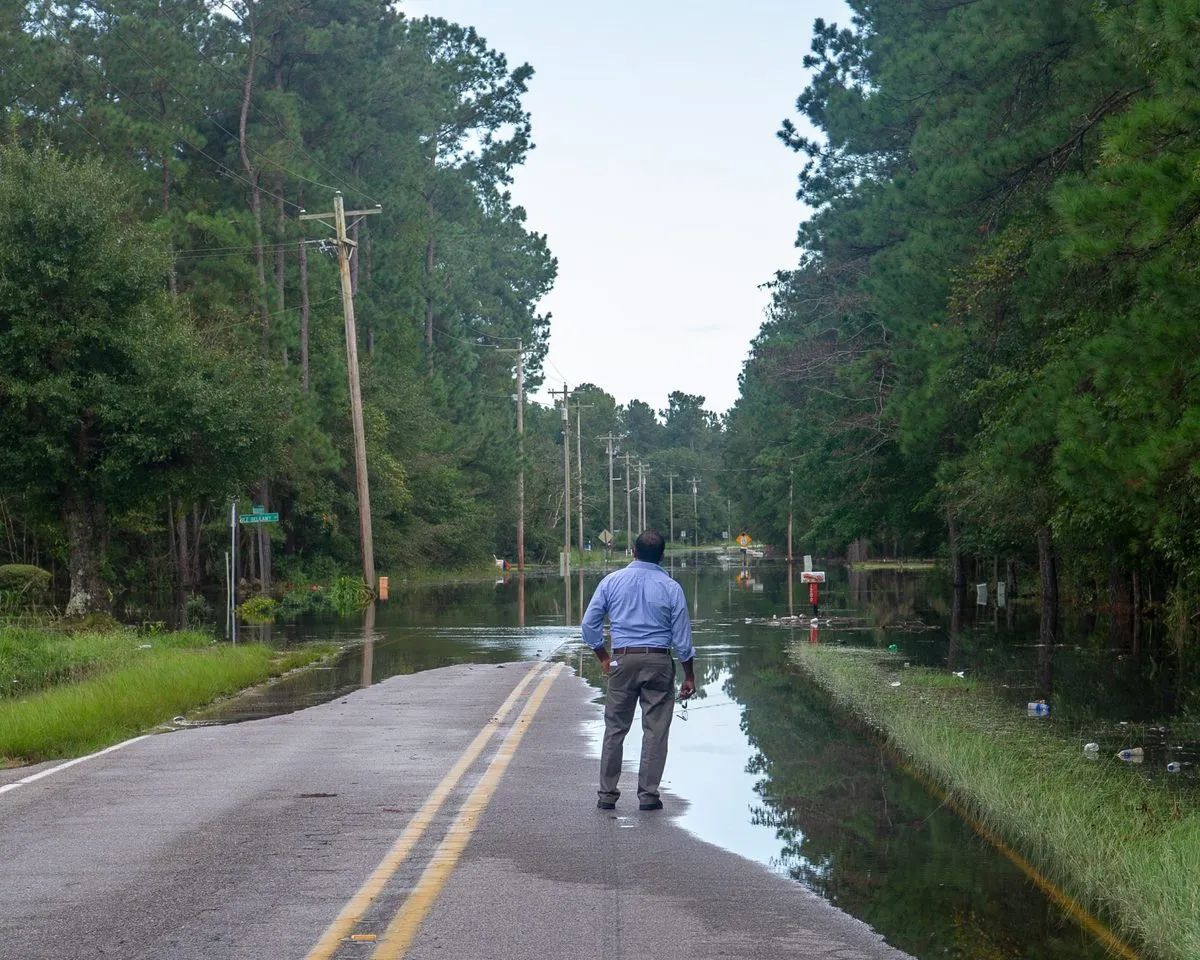 A resident watches floodwater cover a rural road after a hurricane in South Carolina