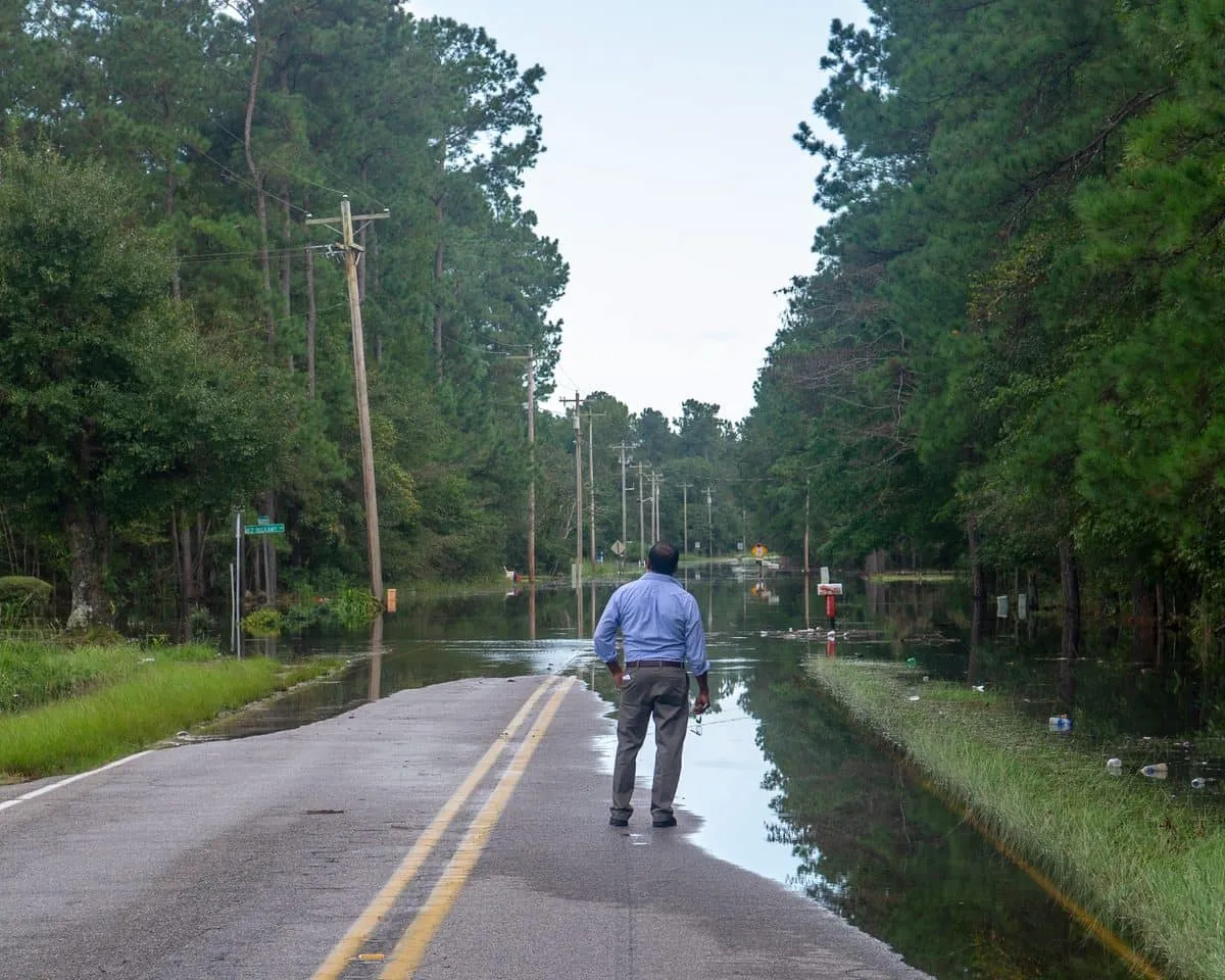 A resident watches floodwater cover a rural road after a hurricane in South Carolina