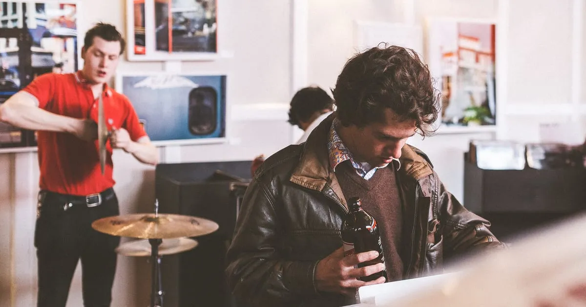 Customers browsing records in a busy independent record shop while a band sets up a drum kit