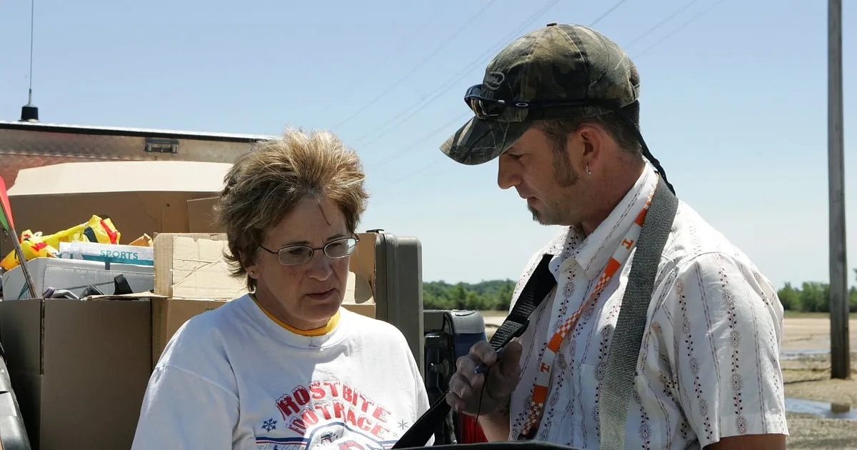 A damage inspector with a tablet asks a homeowner questions next to her packed belongings after a flood