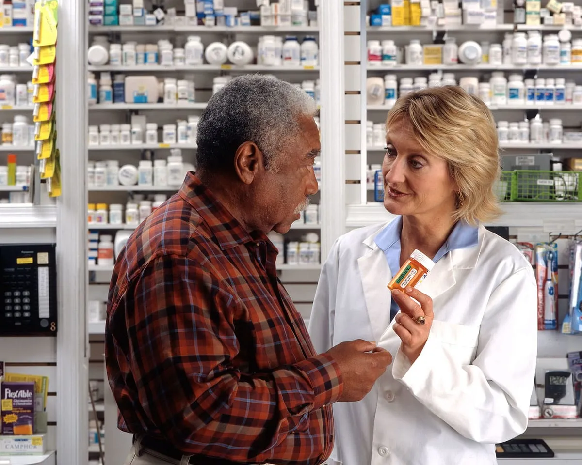 A man reviewing a prescription with his pharmacist, a common qualified HSA expense
