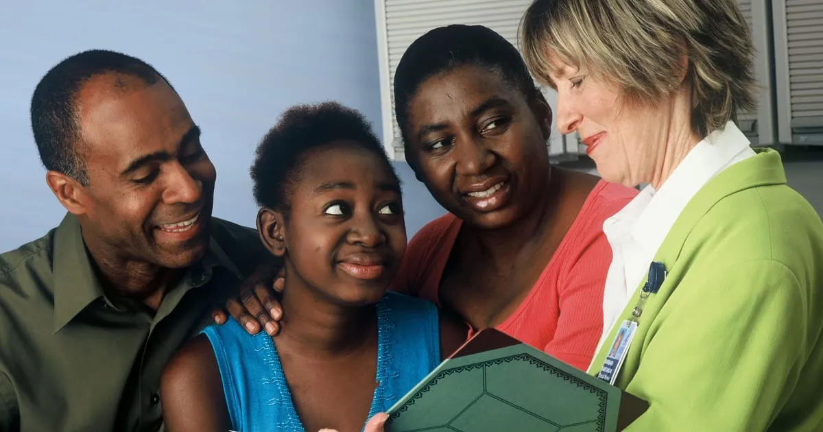 A family of three talking with a health worker who is holding a folder of paperwork